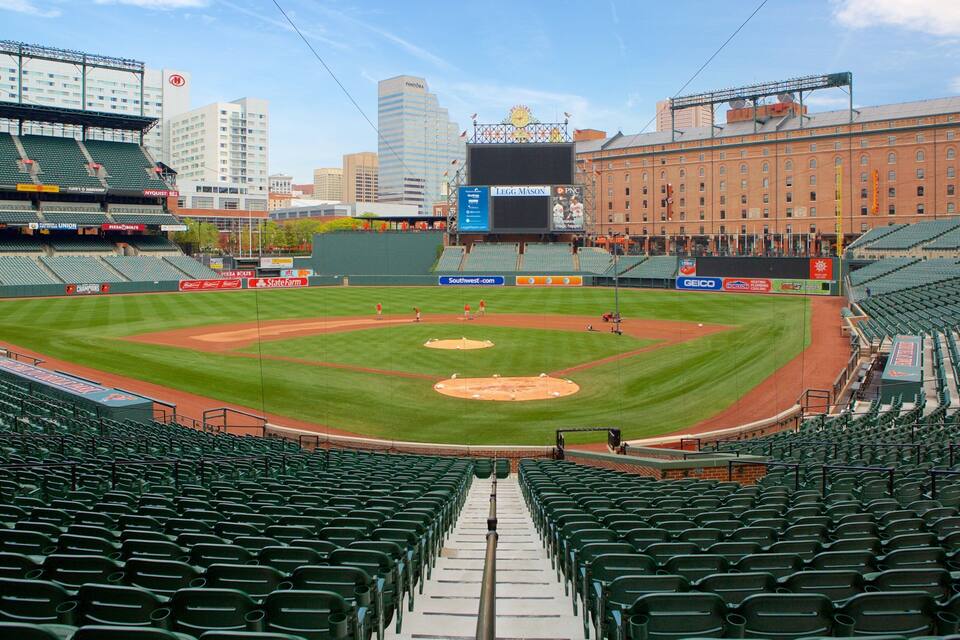 Un estadio de béisbol con asientos verdes, un campo de juego y publicidad.