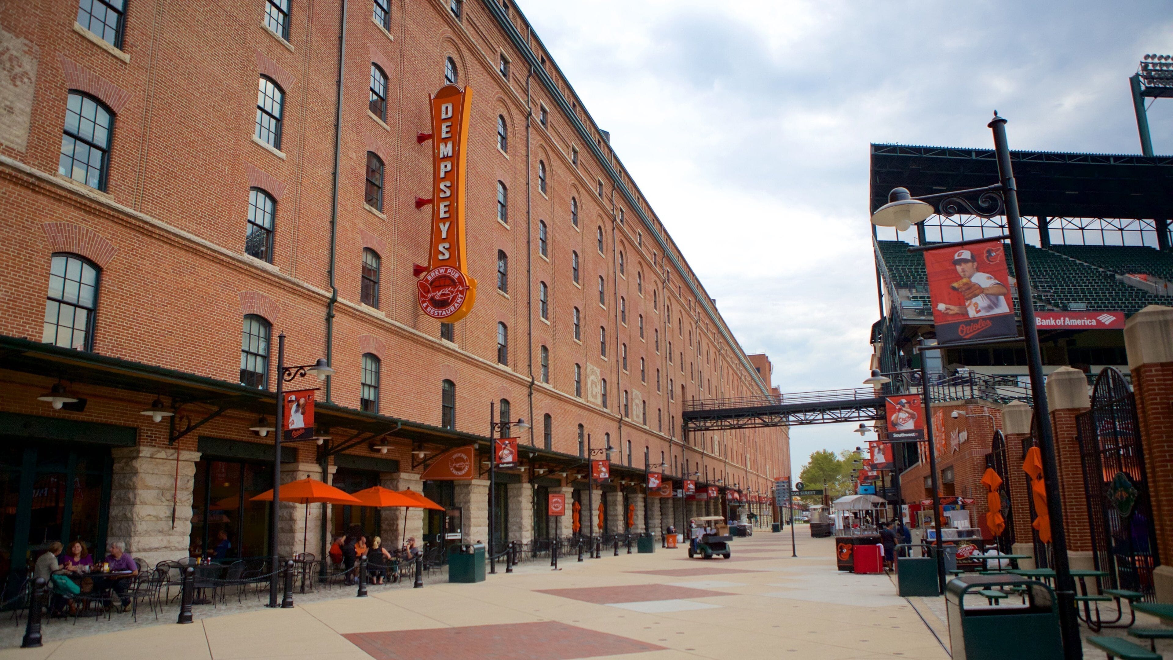 A brick building with a sign reading "Dempsey's Brew Pub & Restaurant" and outdoor seating with orange umbrellas.