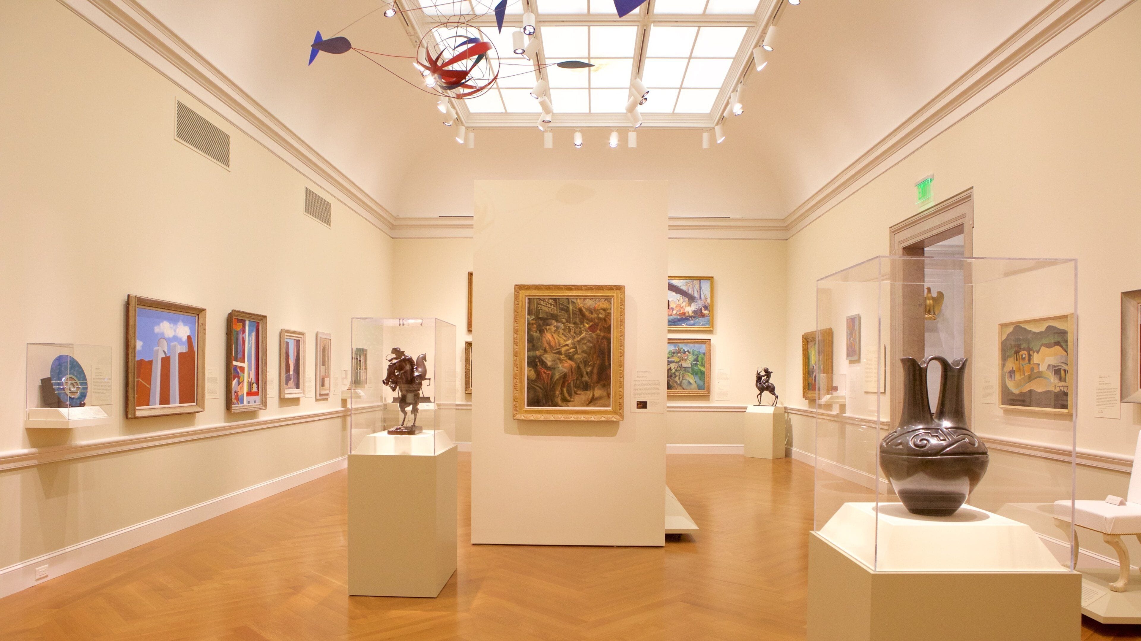 Eine Kunstgalerie mit verschiedenen Gemälden und Skulpturen, die auf Podesten ausgestellt sind.