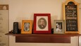 A shelf with framed photographs and a chalkboard with historical information.