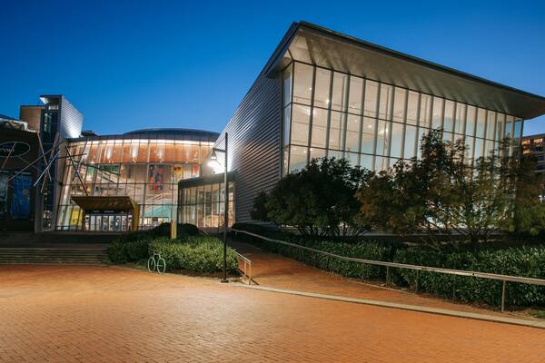 A modern building with large glass windows and a brick pathway leading to it.