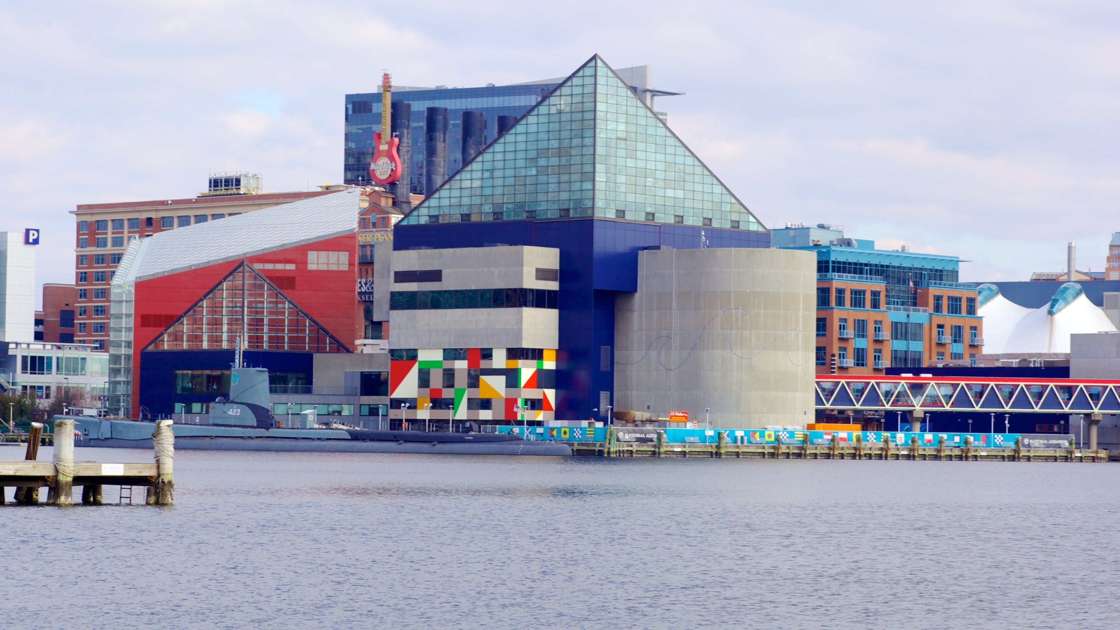 A modern building with a glass pyramid and a red guitar sculpture.
