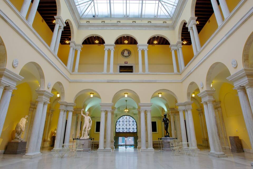 Un salón amplio con techo alto, paredes amarillas y columnas blancas.