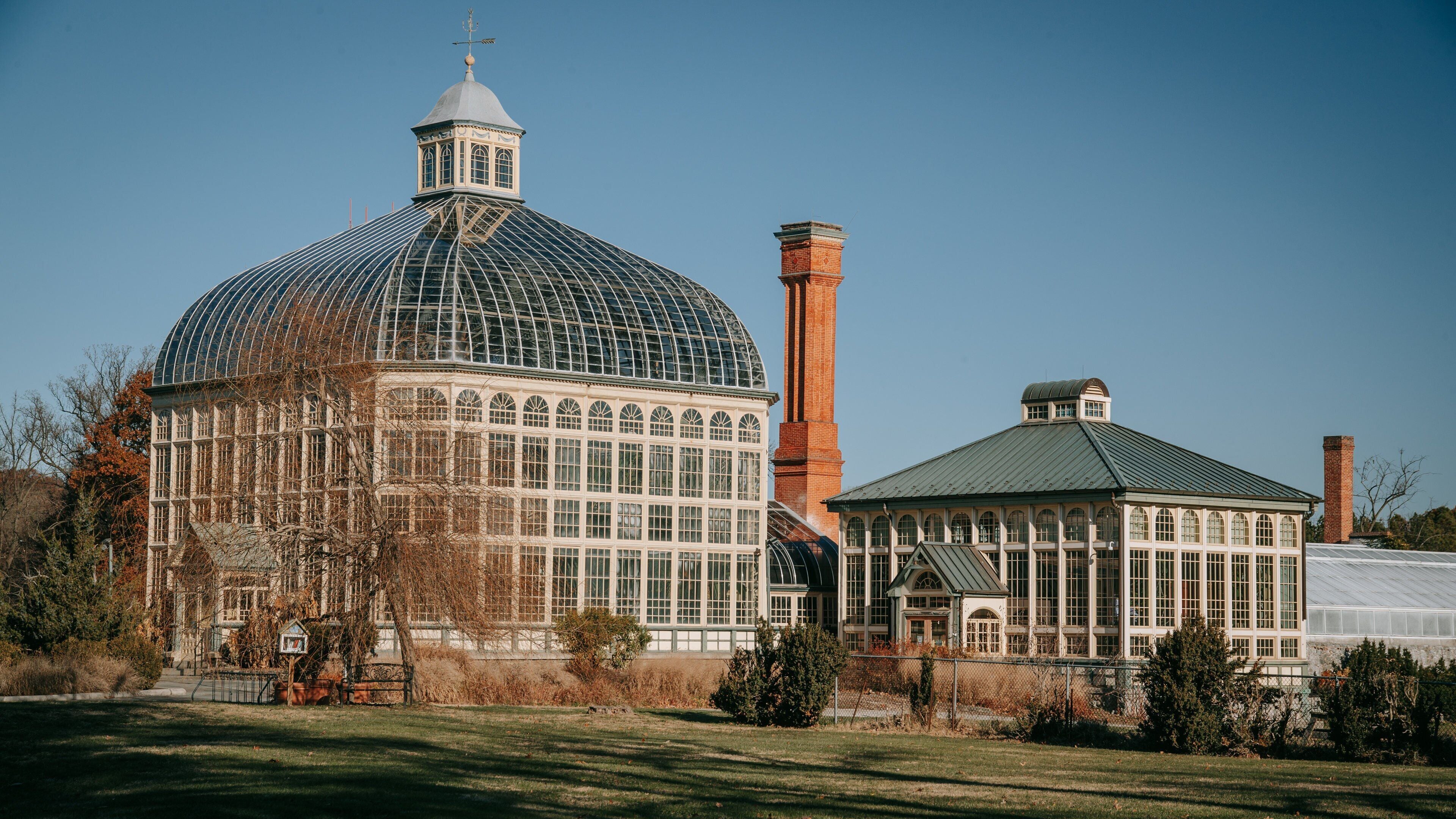A large glass-domed building with a brick chimney and a smaller attached structure with a green roof.
