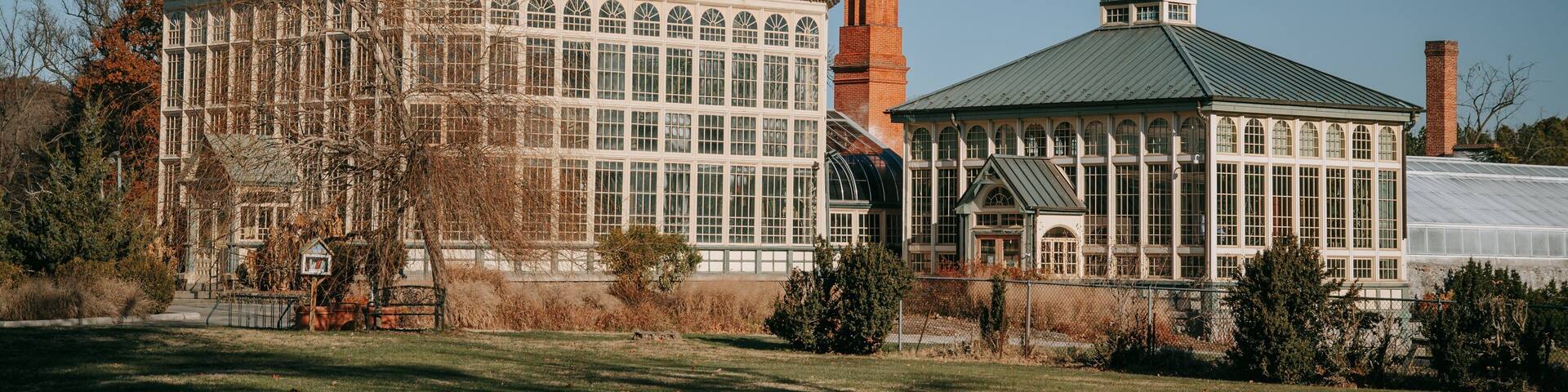 A large glass-domed building with a brick chimney and a smaller attached structure with a green roof.