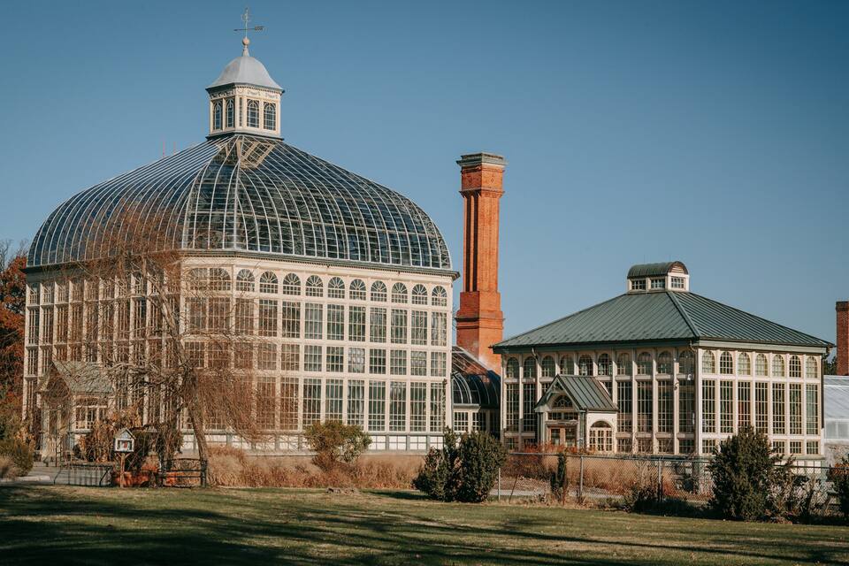 A large glass-domed building with a brick chimney and a smaller attached structure with a green roof.