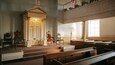 A synagogue interior with wooden benches, a Torah ark, and a candelabrum.