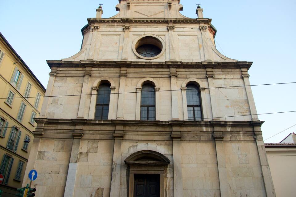 A historic church with a bell tower, arched windows, and a central circular window.