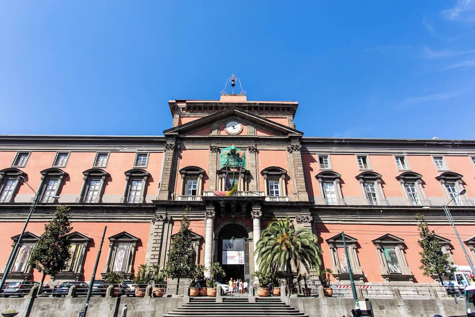 Un edificio histórico con una torre del reloj, ventanas amplias y una entrada principal.