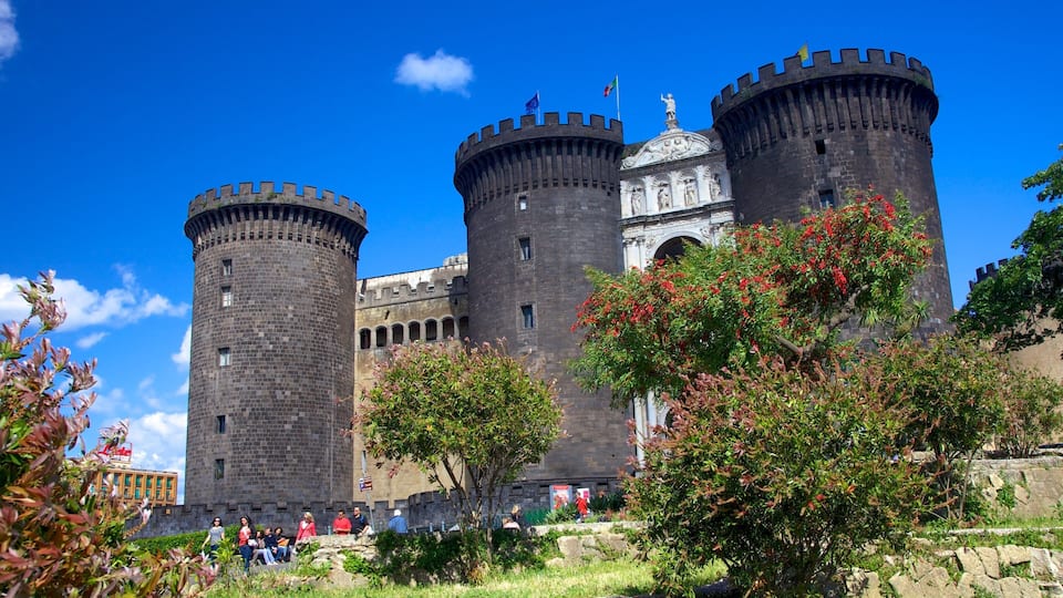 Un castello storico con numerose torri e una cupola centrale, immerso nel verde e con un cielo azzurro limpido.