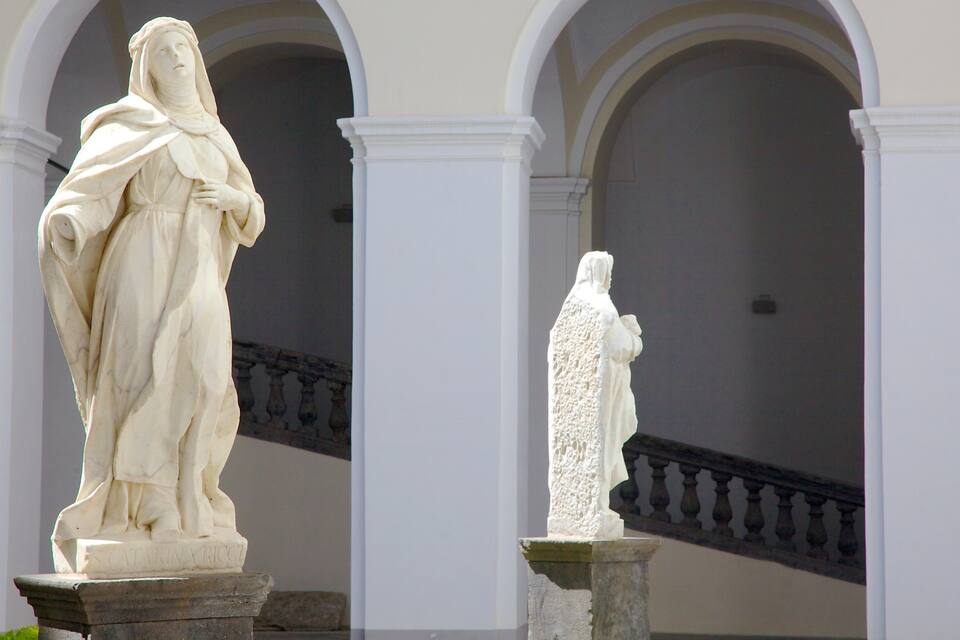 Dues estàtues a l'interior d'un edifici amb arcs i una escala.
