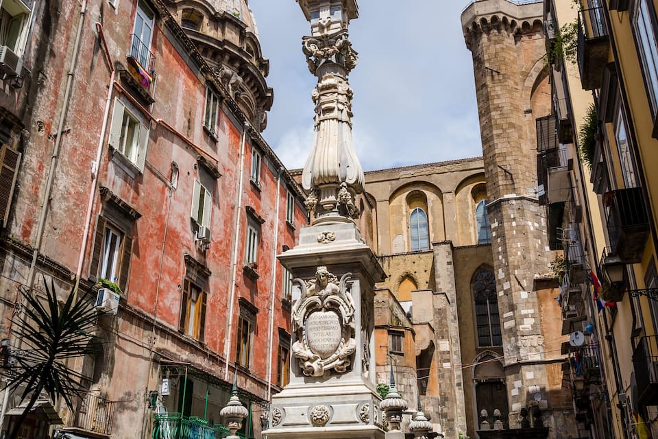 A historic fountain with intricate sculptures in a European city square surrounded by old buildings.