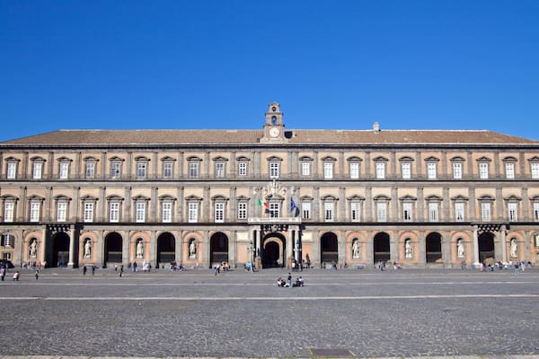 Un grand bâtiment historique doté d’une tour horloge et de nombreuses arcades.
