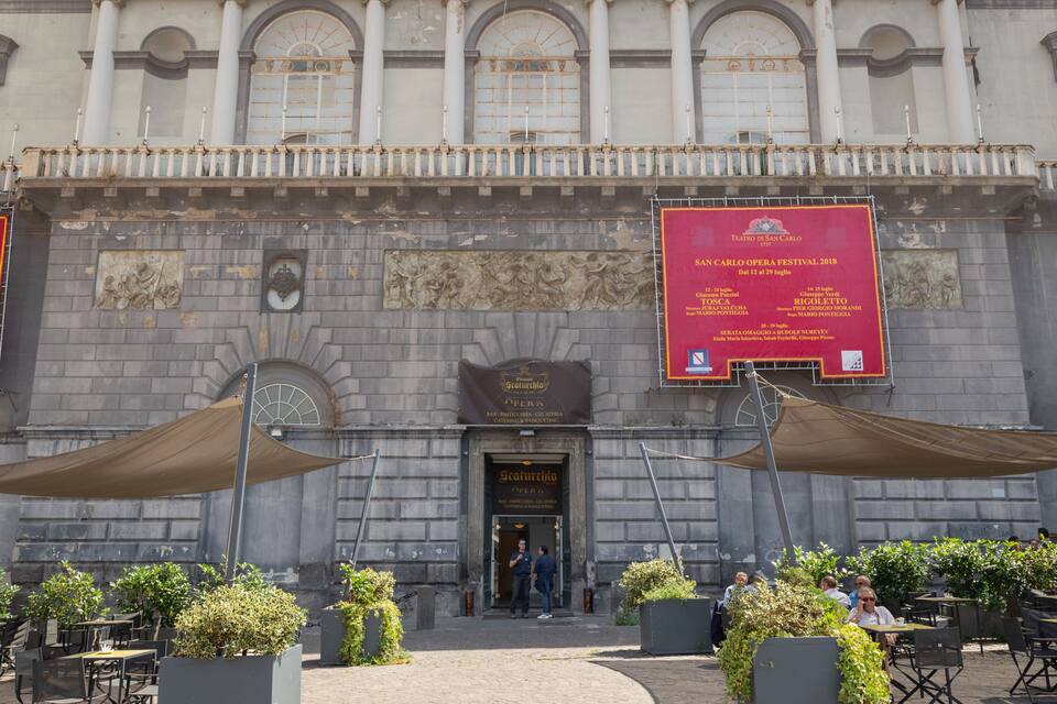 Teatro di San Carlo with outdoor seating and banners advertising events.