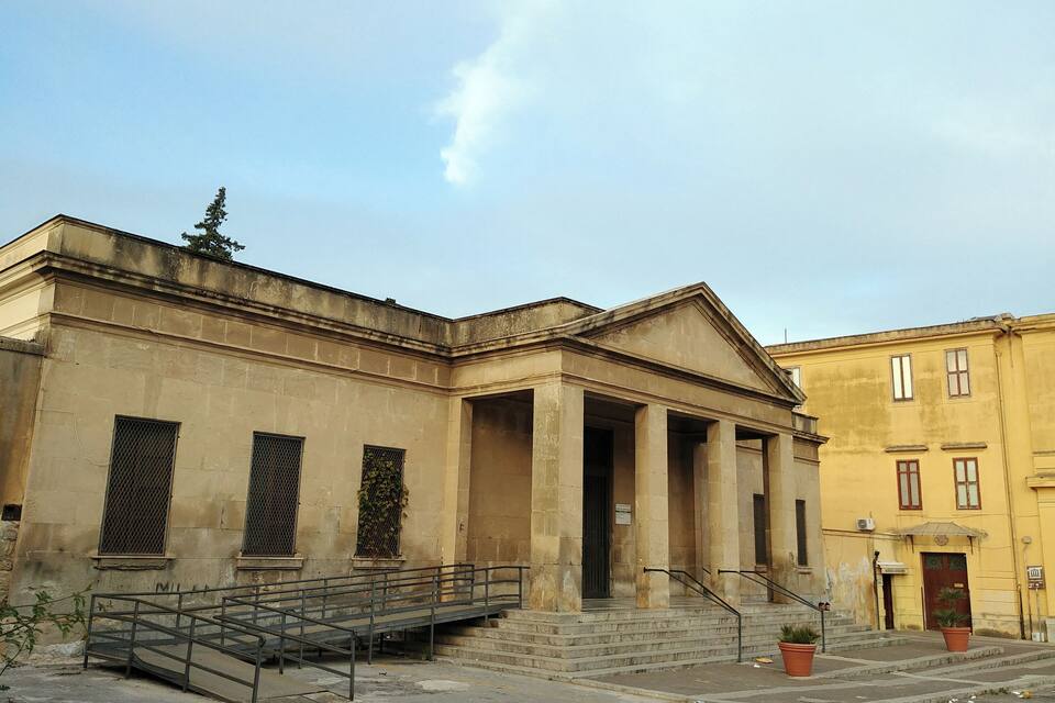 A classical building with columns, a staircase, and a metal railing.