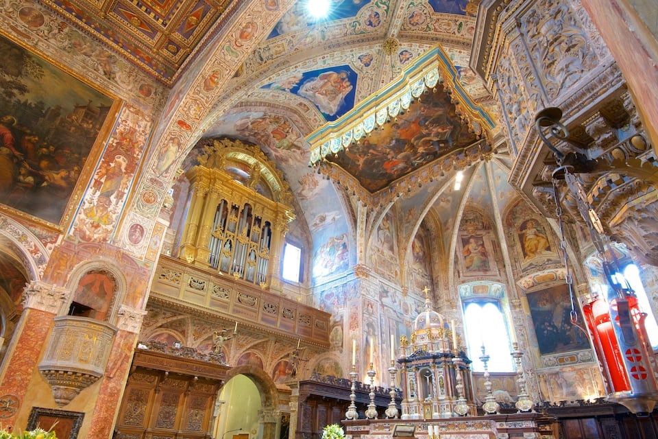 An ornate church interior with detailed frescoes, a large organ, and a cross.