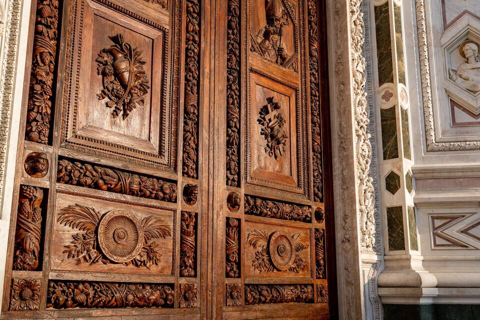 Uma porta de madeira detalhada com esculturas elaboradas de frutas e folhagens.