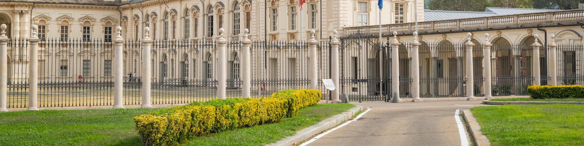 A grand historic building with classical architecture, featuring columns, a large entrance, and flags.