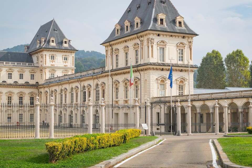 A grand historic building with classical architecture, featuring columns, a large entrance, and flags.