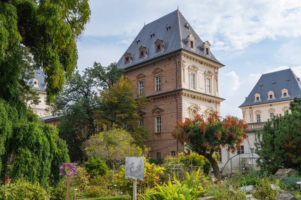 A historic building with a steep roof and a garden in front.