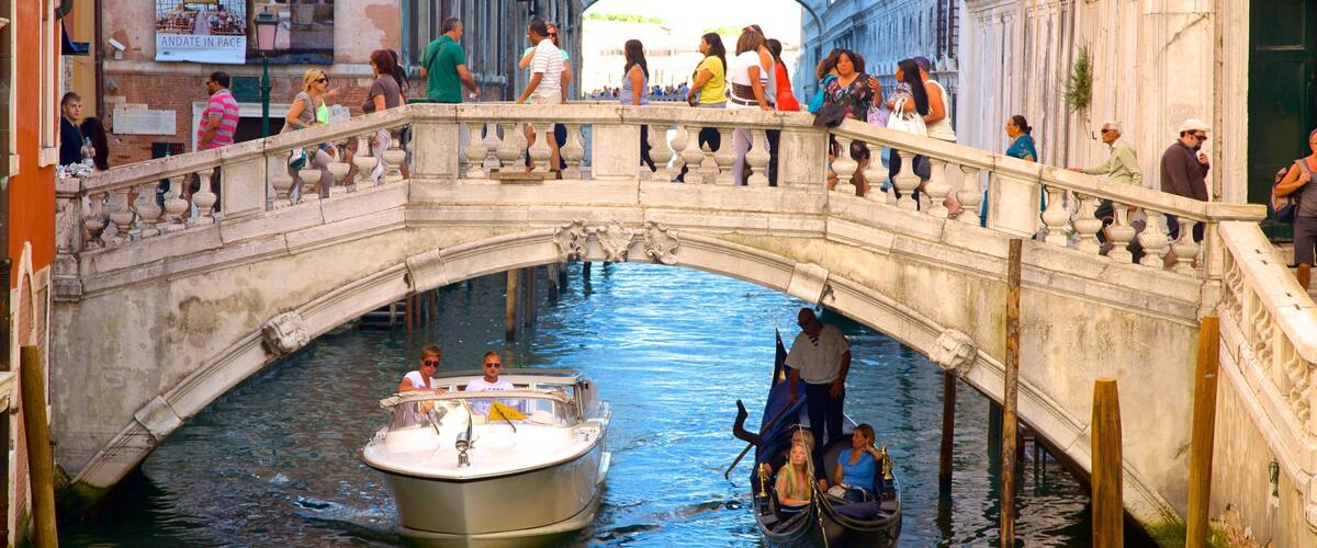 A historic stone bridge over a canal with gondolas and tourists.