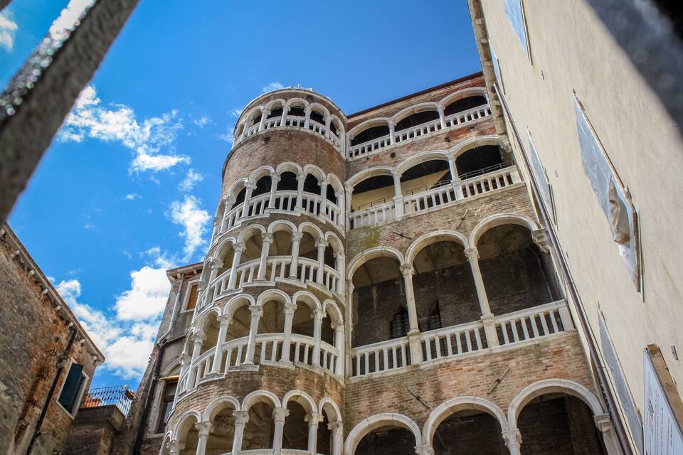 Un bâtiment historique doté de nombreuses arcades et de balcons, sous un ciel bleu dégagé.