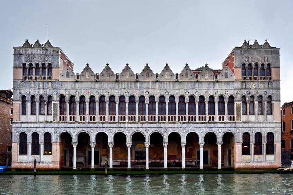 A historic building with a row of arches and a series of pointed towers.