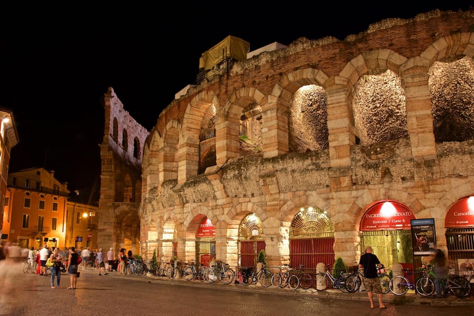 Um edifício histórico iluminado com arcos e uma placa com a inscrição