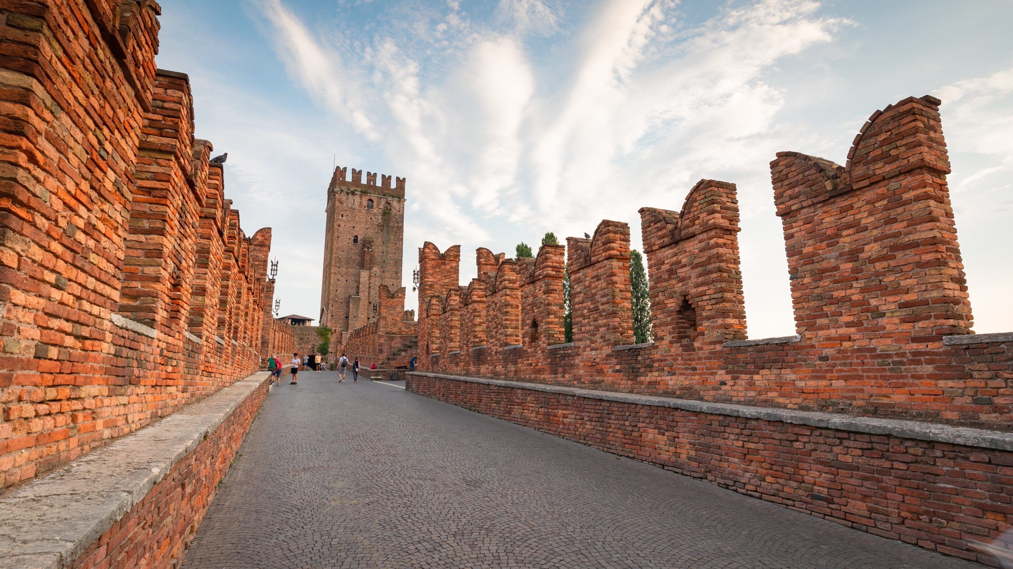 A historic brick wall with a tower in the background.