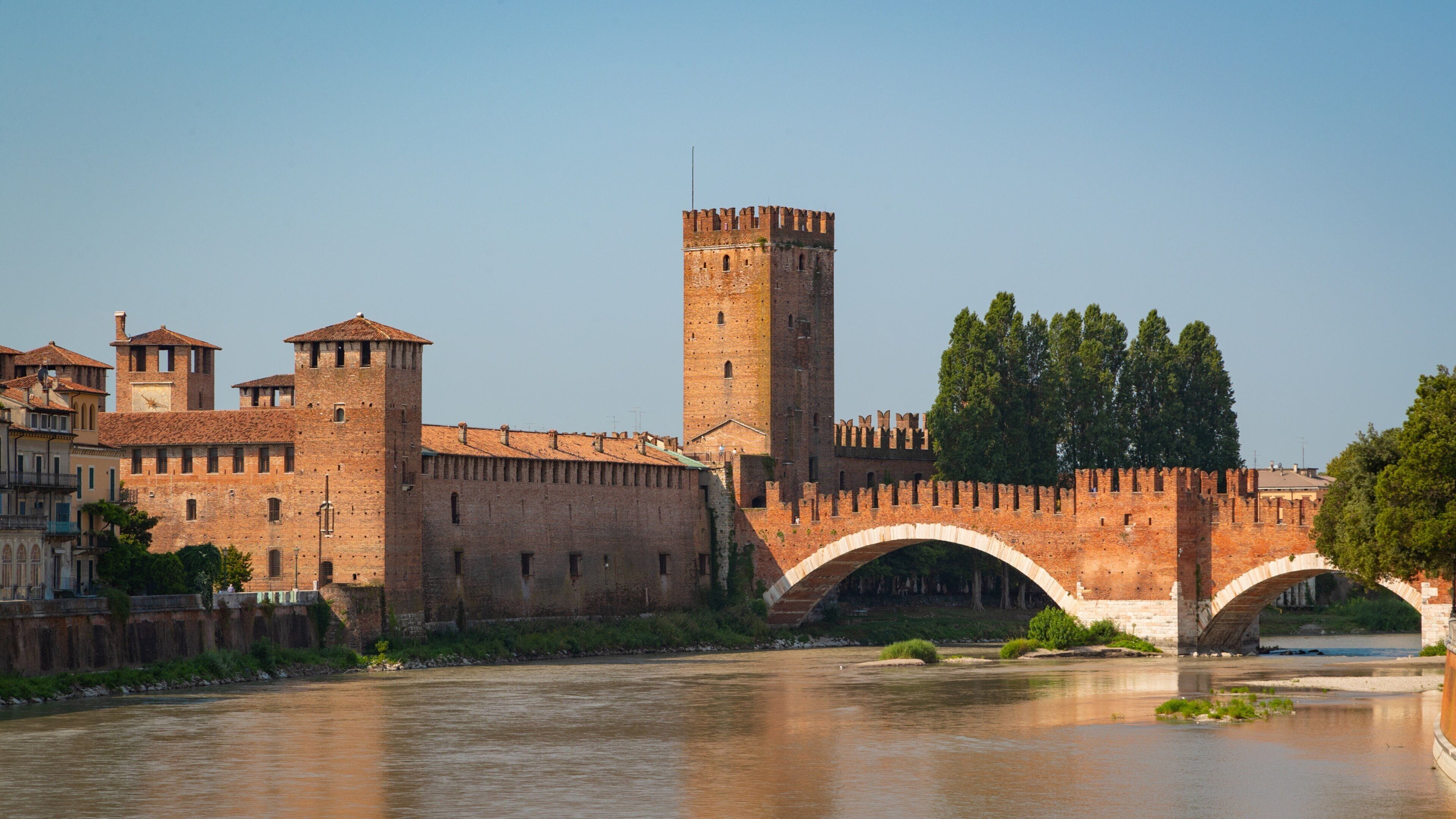 A historic stone bridge over a river, with a tall tower and medieval buildings on either side.