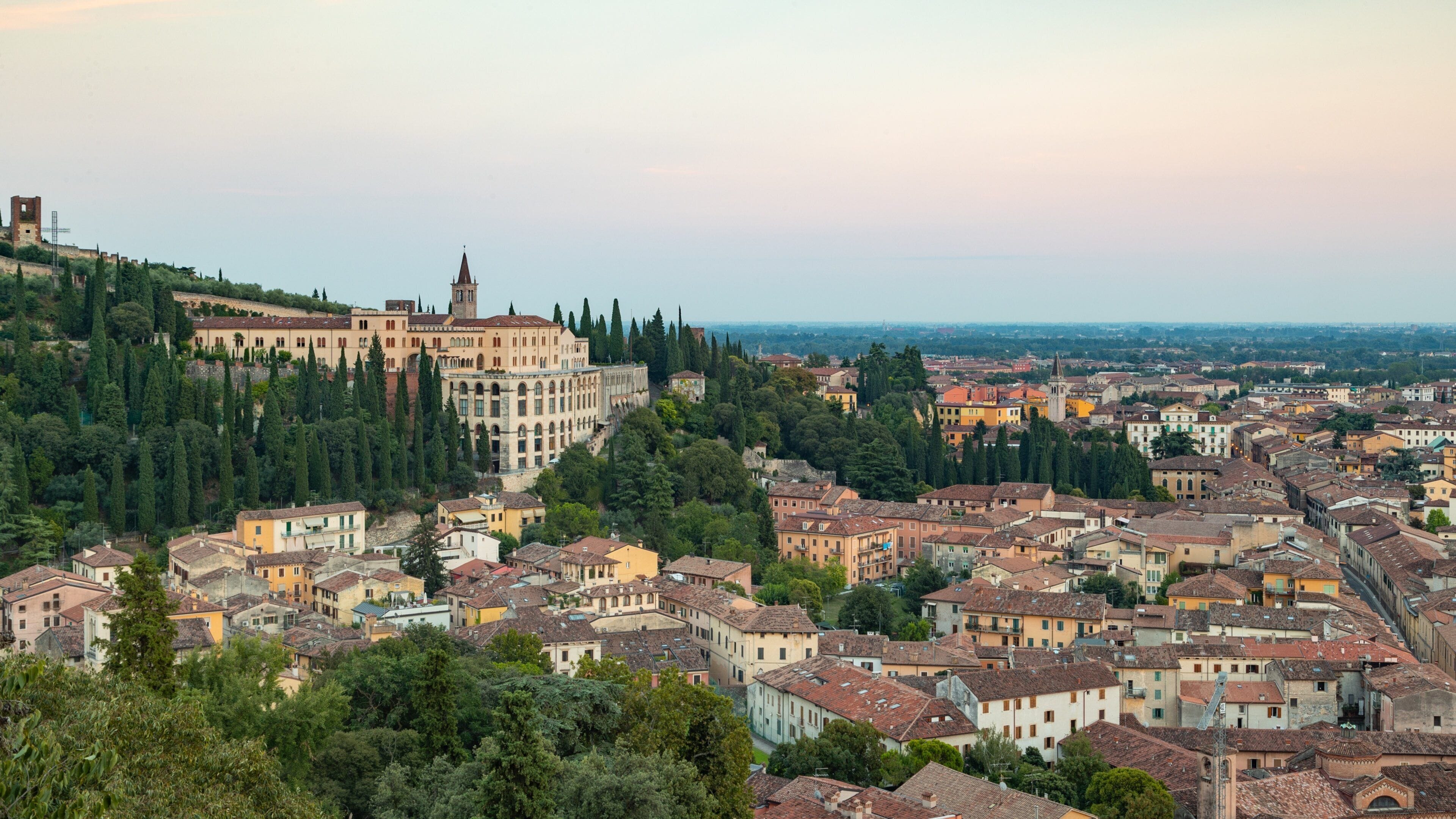 A historic town with a prominent church and castle on a hill, surrounded by dense greenery and traditional buildings.