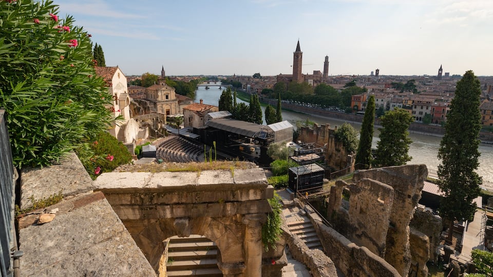 Ancient ruins with a river, a tower, and a cityscape in the background.