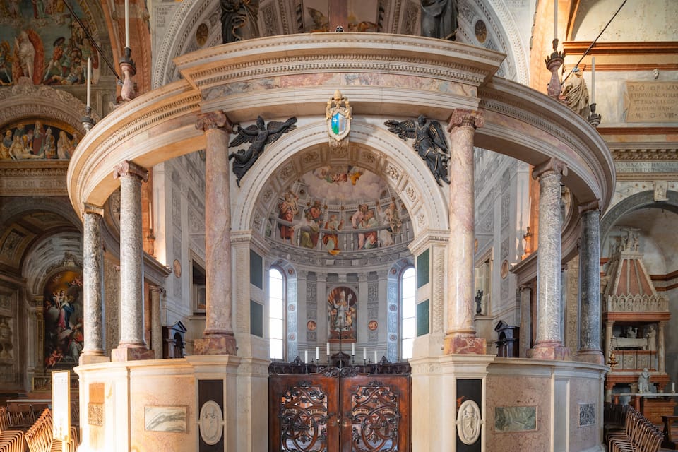 Interior de igreja ornamentado, com altos tetos, frescos detalhados e colunas clássicas.