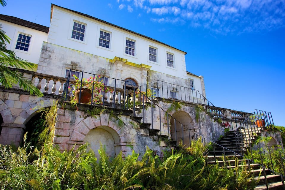 Un edificio blanco con ventanas arqueadas y una escalera que sube a un balcón.