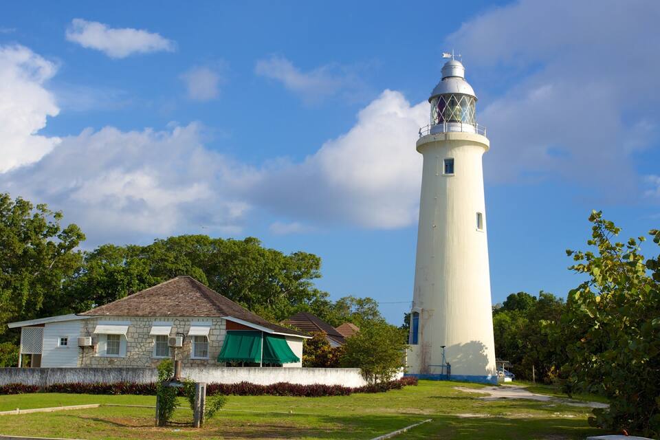 A lighthouse with a white tower and a green-roofed building in the foreground.