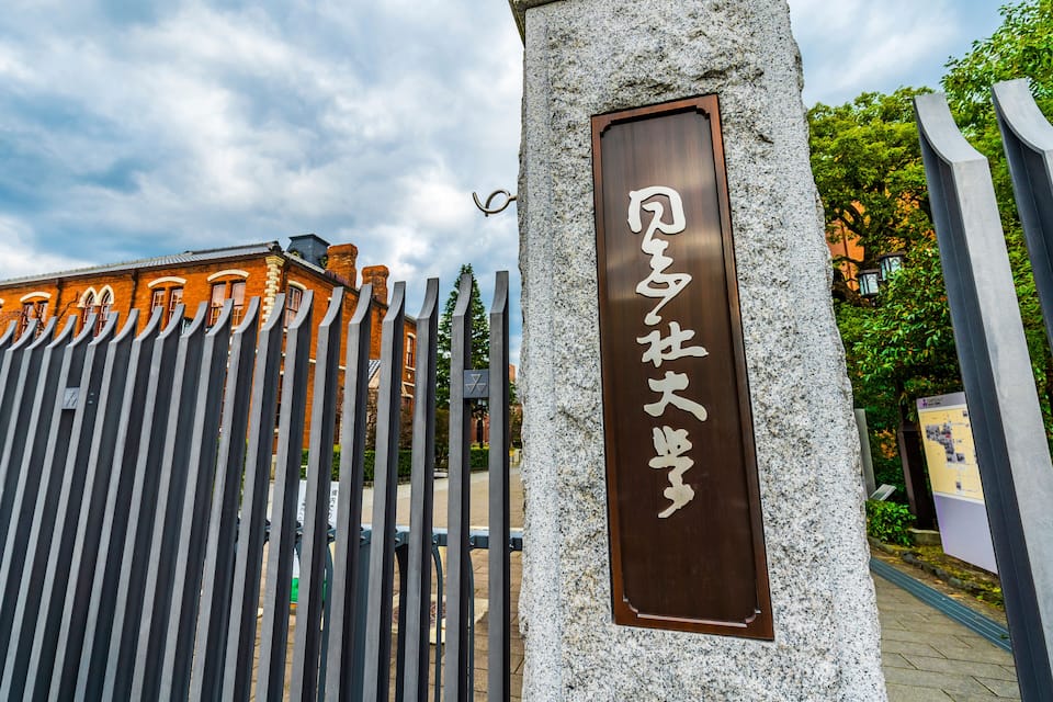 A stone pillar with a plaque and a metal fence with vertical bars.