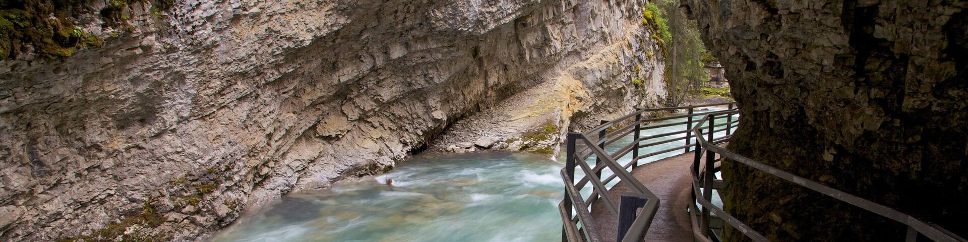 Johnston Canyon featuring a river or creek, rapids and landscape views