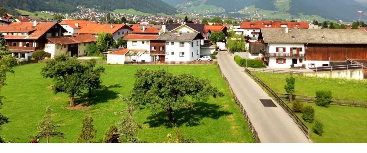 A village with red-roofed houses, a road, and green fields.