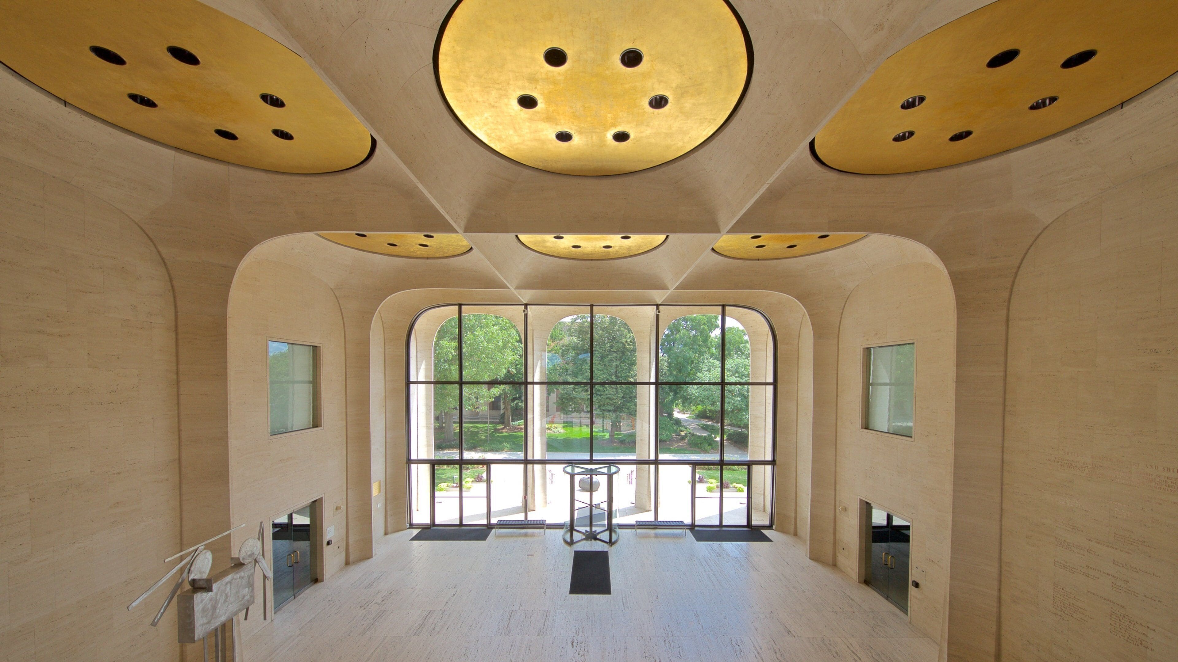 A modern interior with large arched windows, a central column, and a ceiling with circular cutouts.