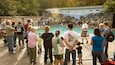 Un groupe de personnes observe une piscine, avec un paysage rocheux et une fresque murale en arrière-plan.