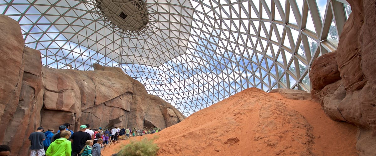 A geodesic dome structure with a rocky landscape and a crowd of people.