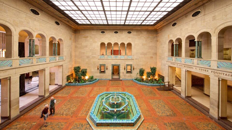A grand atrium with a central fountain, arched colonnades, and a tiled floor.