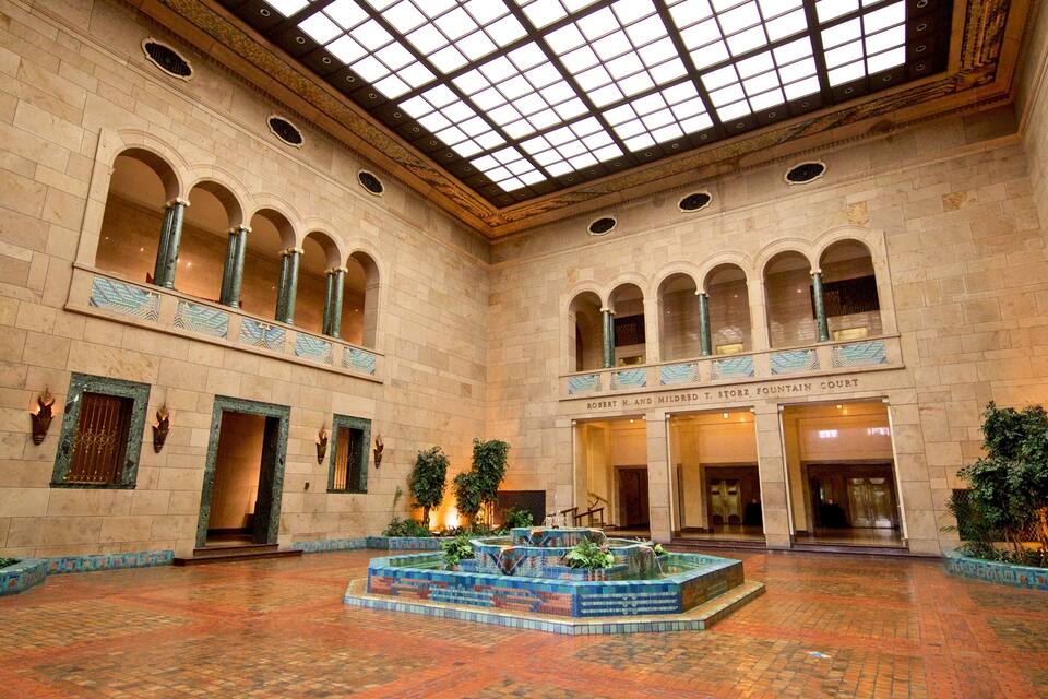 A grand hall with a high ceiling, arched windows, and a central fountain.