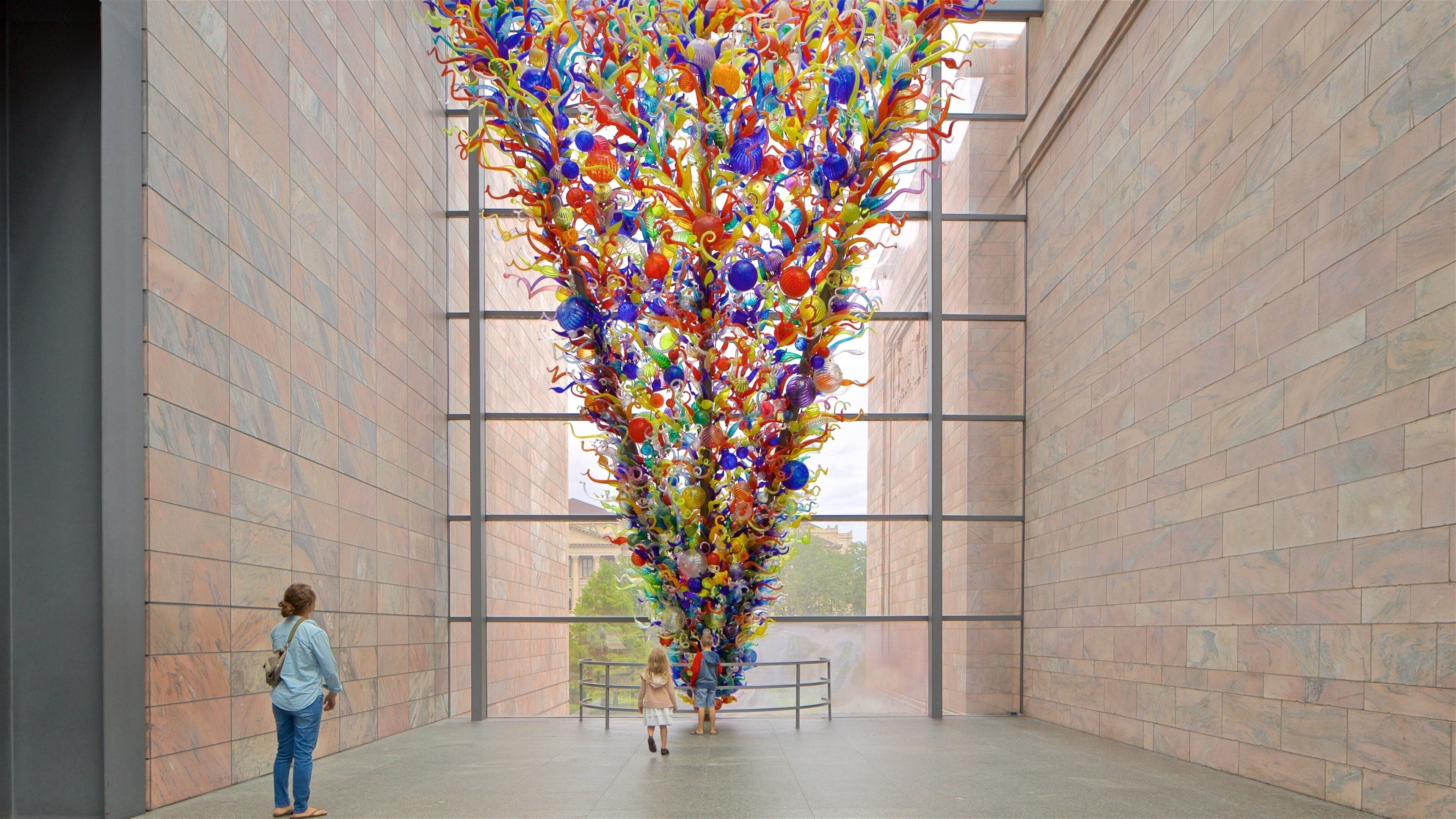 Eine große Glaskunstinstallation in einem modernen Gebäude mit Fliesenwänden und großen Fenstern.