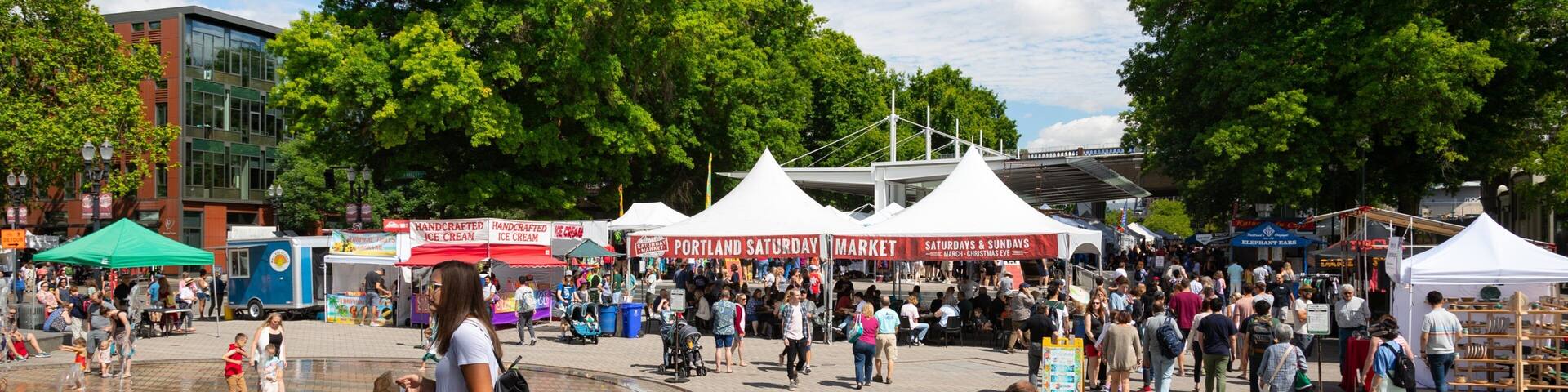 Portland Saturday Market showing markets and a fountain as well as a large group of people
