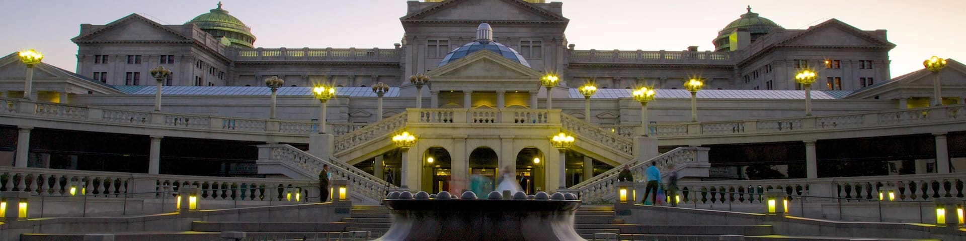 A grand building with a large central dome and a fountain in front.