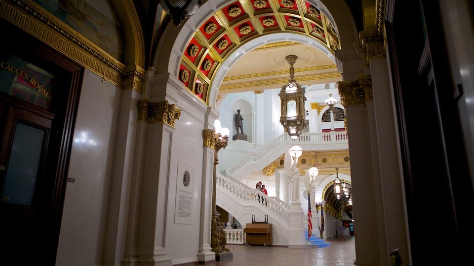 An ornate interior with a grand staircase, golden decorations, and a statue.
