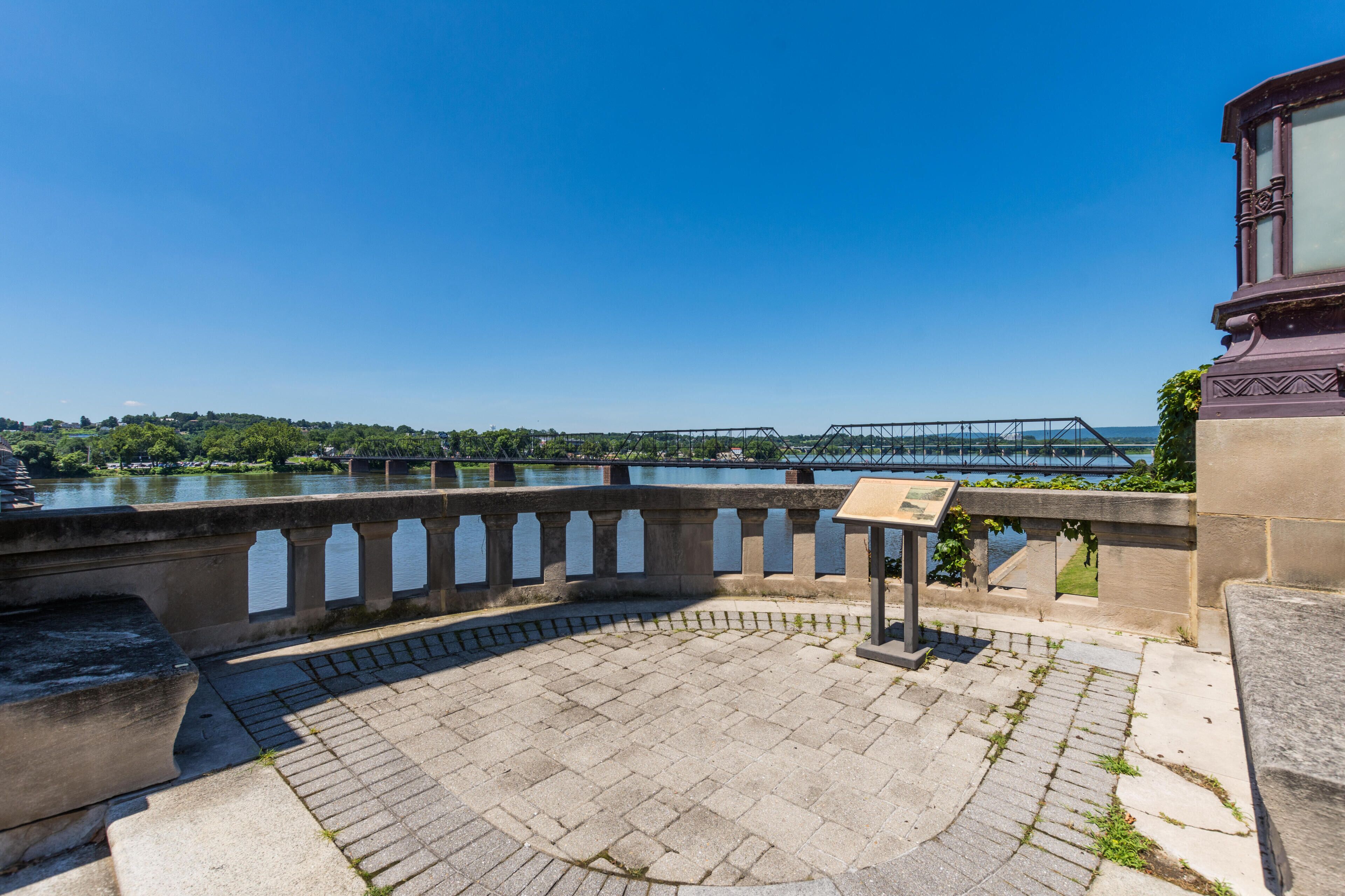 A stone bridge over a river, a stone walkway, and a metal bridge in the distance.