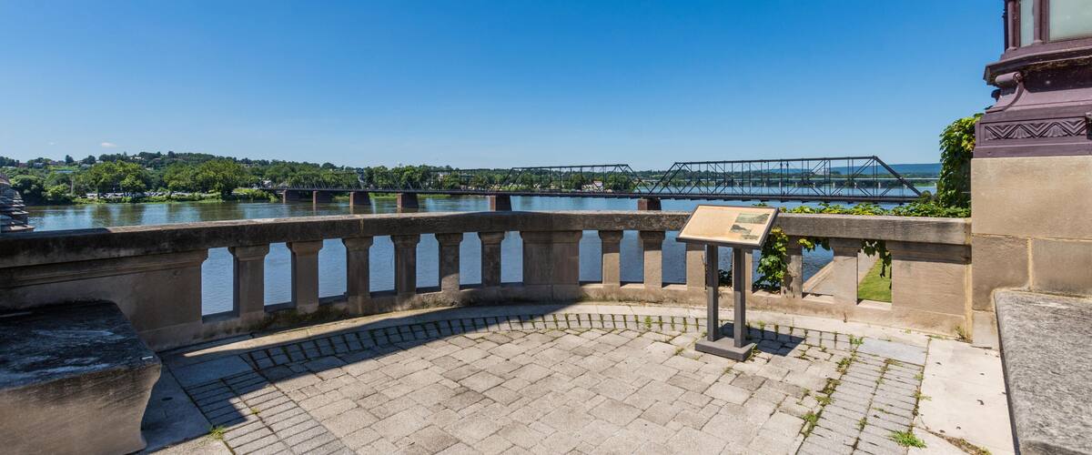 A stone bridge over a river, a stone walkway, and a metal bridge in the distance.