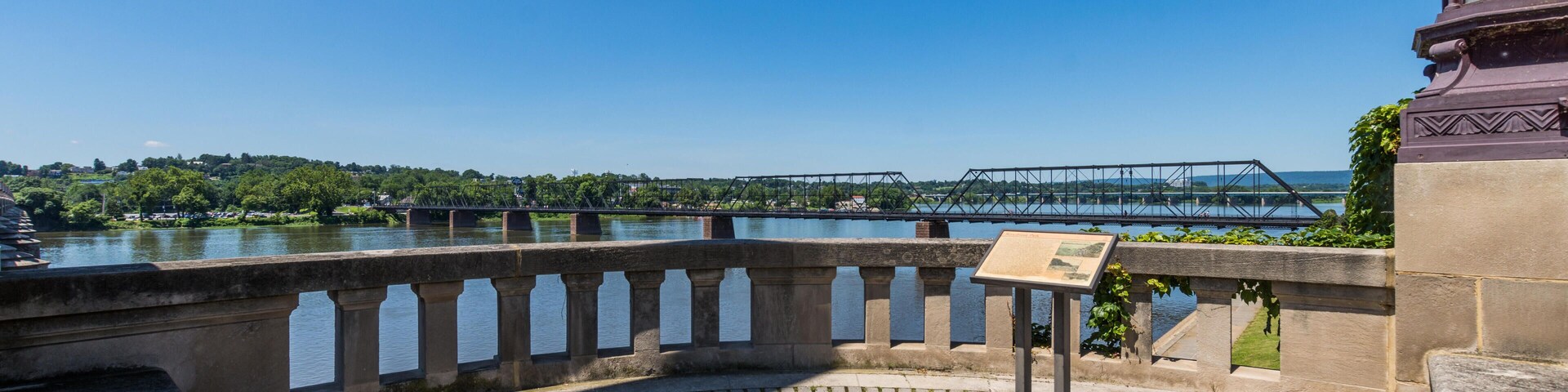 A stone bridge over a river, a stone walkway, and a metal bridge in the distance.